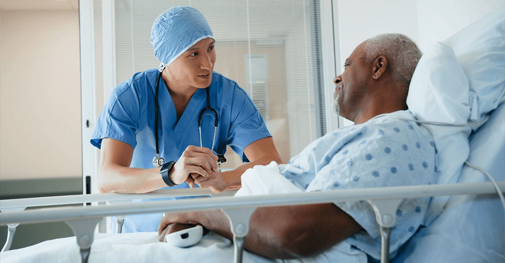 Surgeon patiently discussing care with a patient in the hospital ward.