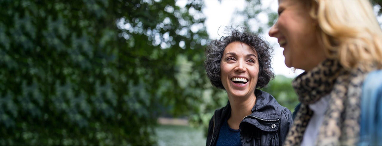 Two women smiling happily in nature, enjoying pain-free movement.