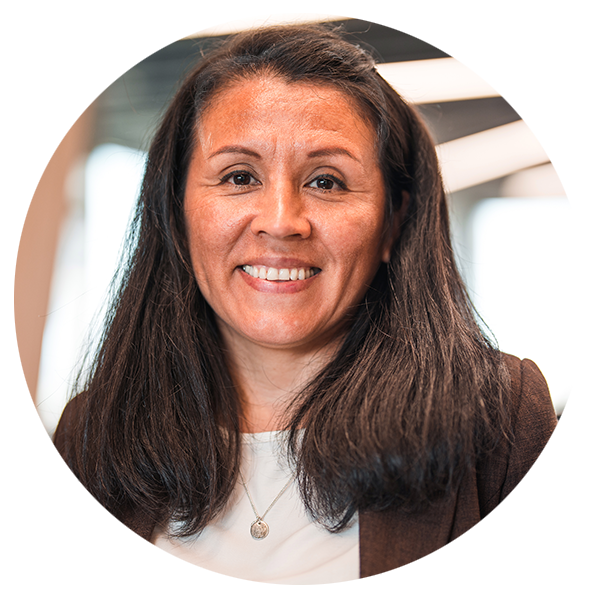 A confident female pain management doctor standing in the office and smiling at the camera.