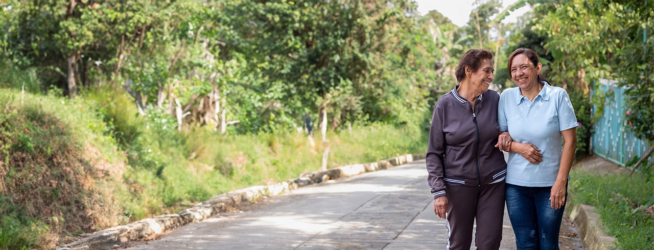 Elderly mother and daughter share a joyful, smiling moment during a morning walk.