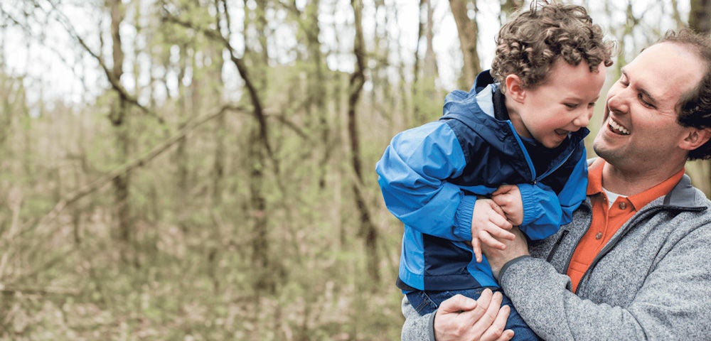 Father and son joyfully interacting with each other in a forest.