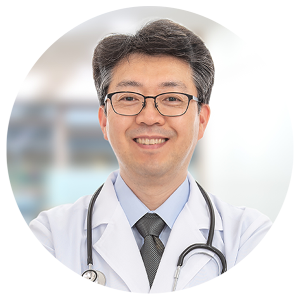 Male surgeon smiling at the camera with a hospital background.