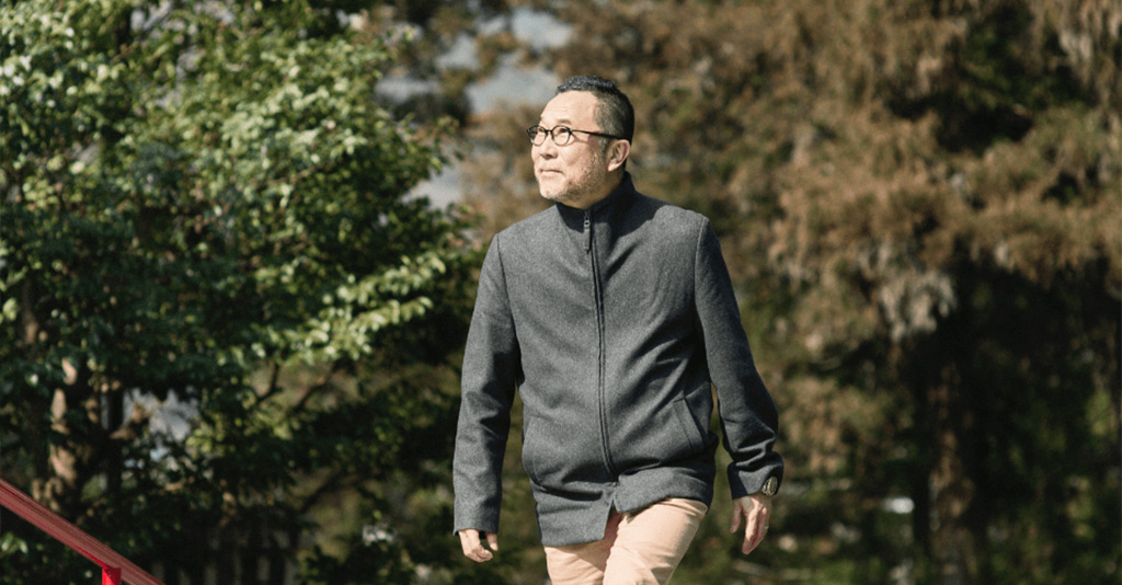 A man walking across a bridge in a wooded area.