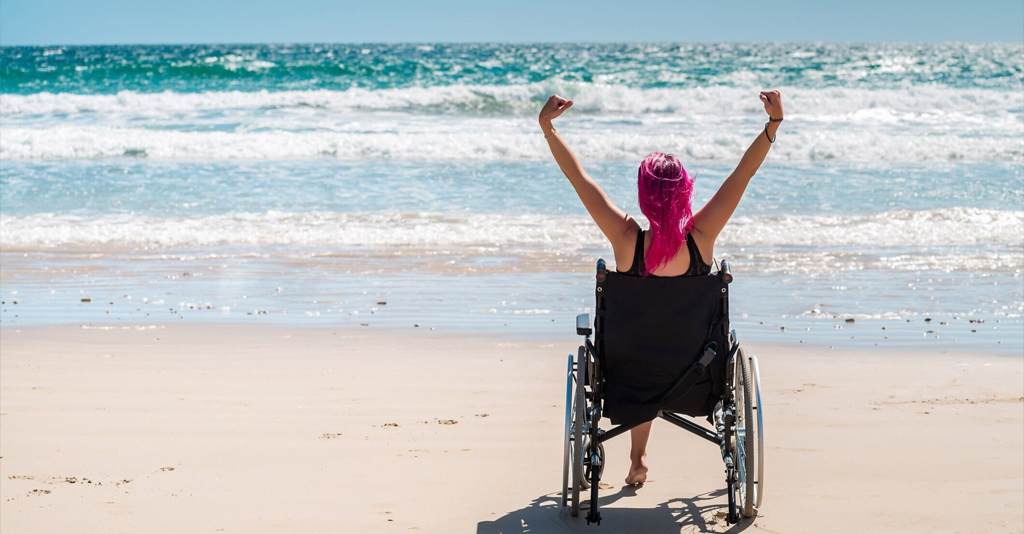 Disabled woman in the wheelchair at the beach.