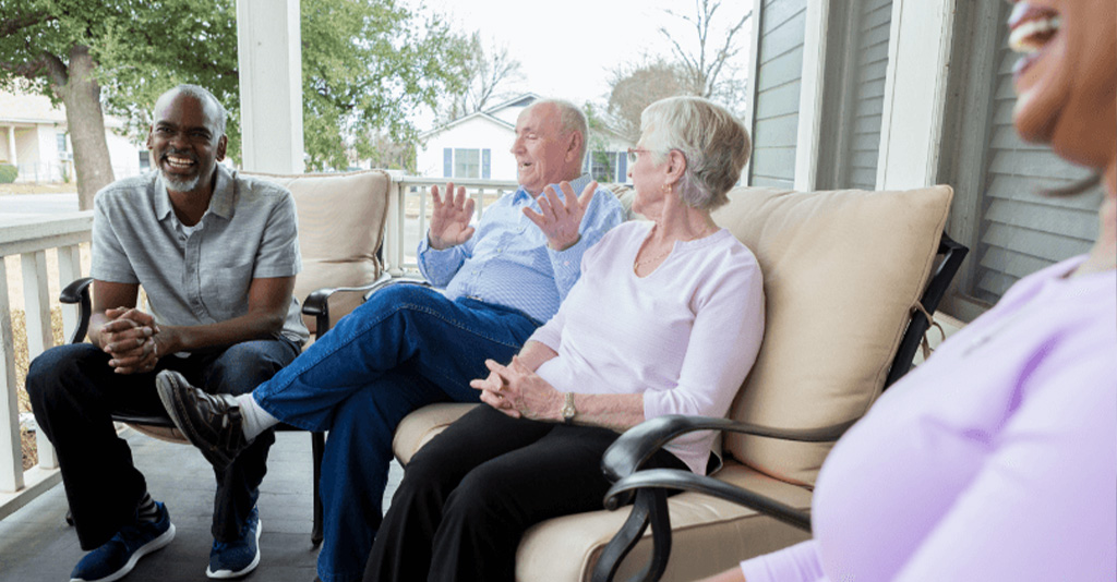 A group of people sitting on a porch talking.