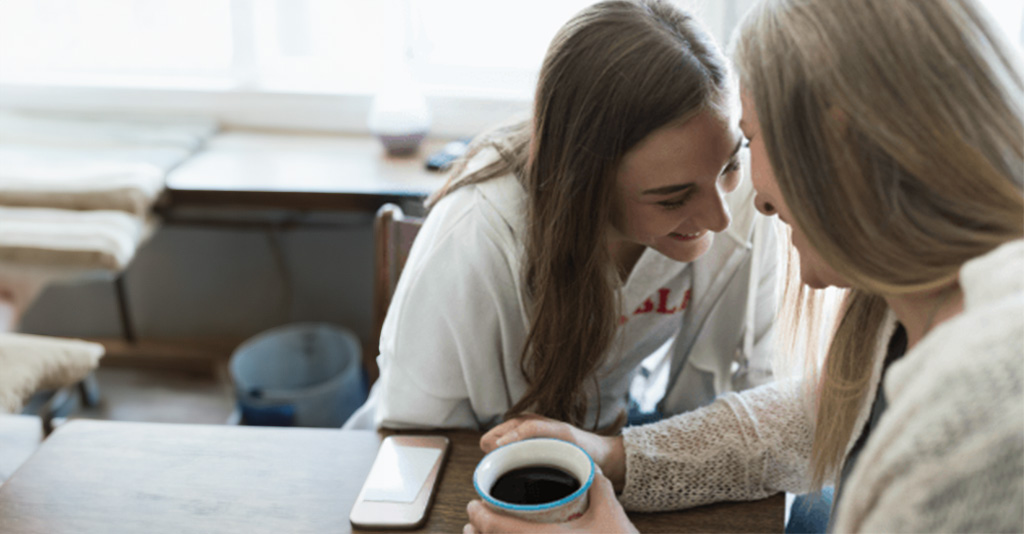 Two women sitting at a table talking.