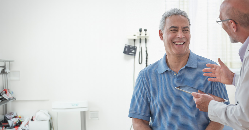 A doctor holding a tablet talking to a patient.