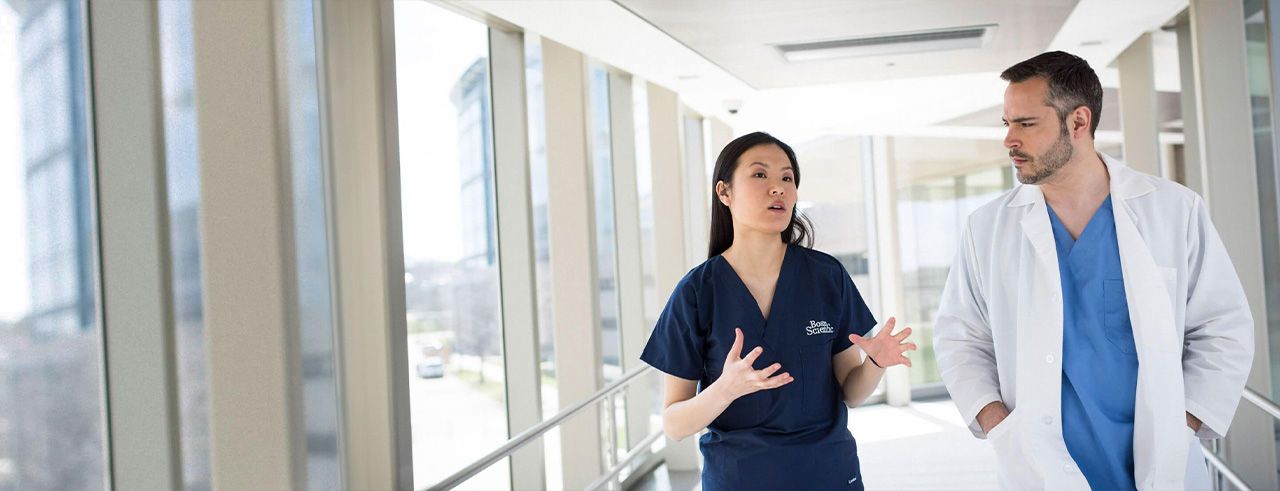 Physican doing conversation while walking in hospital.